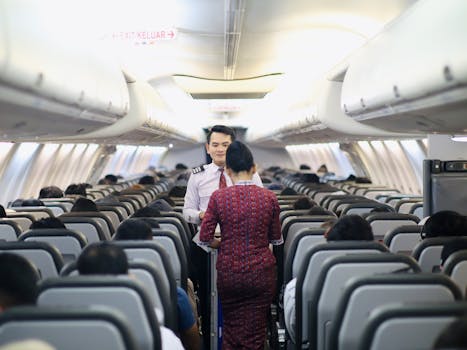 Flight attendants serving passengers inside an airplane cabin during a flight.